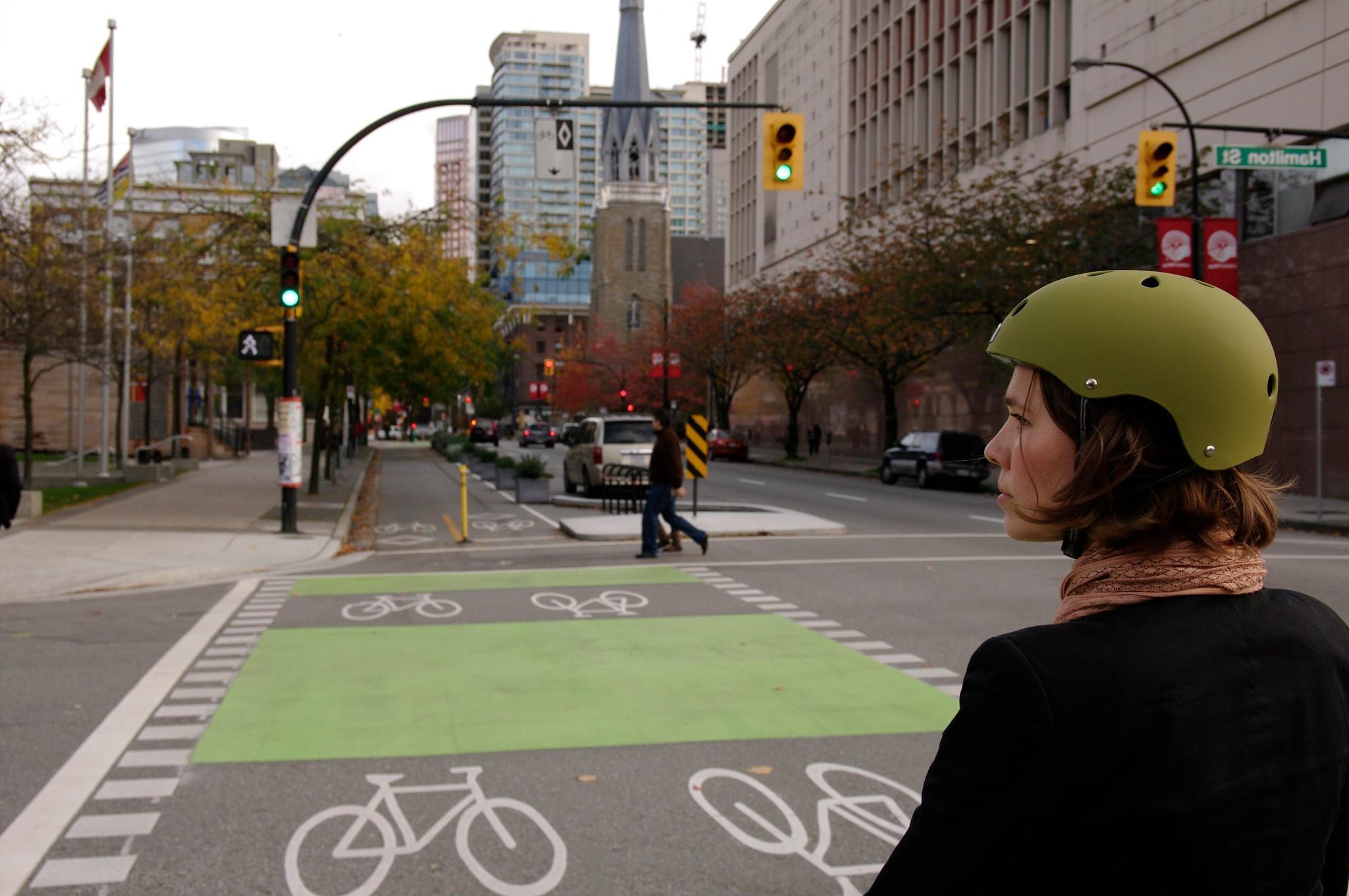 Woman facing a separated bicycle lane on Dunsmuir Street, downtown Vancouver, Canada